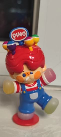 美颜赛道必须有PINO棒棒糖一席之地！PINO这只娃的颜值直接戳中萌点！红扑扑的脸蛋缀着圆嘟嘟的橘色腮红，蓝紫撞色的眼睛像藏了星星，嘴角叼着棒棒糖软萌到爆。红卷发顶缀着彩色棒棒糖和PINO徽章，红白条